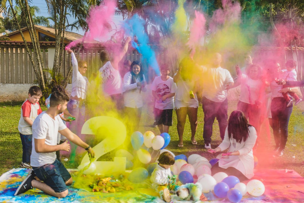 Fotografia de toda a família jogando tinta em pó para cima durante o ensaio infantil paint em Mongaguá - Cia P&B - Fotografia