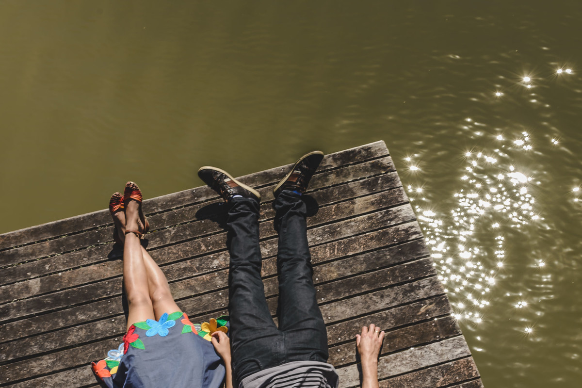 Foto dos noivos deitados apenas as pernas aparecendo no trapiche na beira do lago no Parque Tanguá no ensaio pré wedding - Curitiba - fotografia Cia P&B Produções 