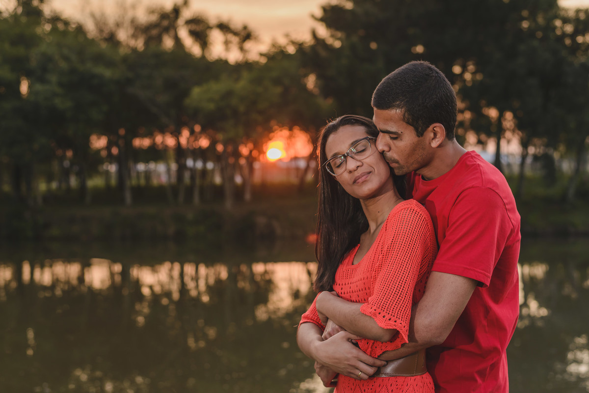 Foto dos Noivos abraçados de olhos fechados com o pôr do sol ao fundo e lago do Parque São José dos Pinhais - PR- no ensaio pré wedding - fotografia Cia P&B Produções 