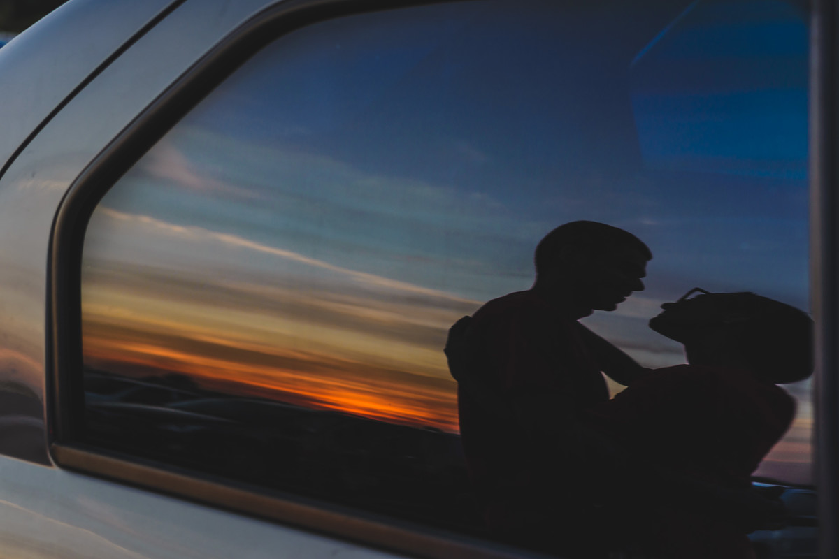 Foto de Silhueta e reflexo dos noivos no vidro do carro com o pôr do sol ao fundo no parque São José dos Pinhais - PR - no ensaio pré wedding - fotografia Cia P&B Produções 