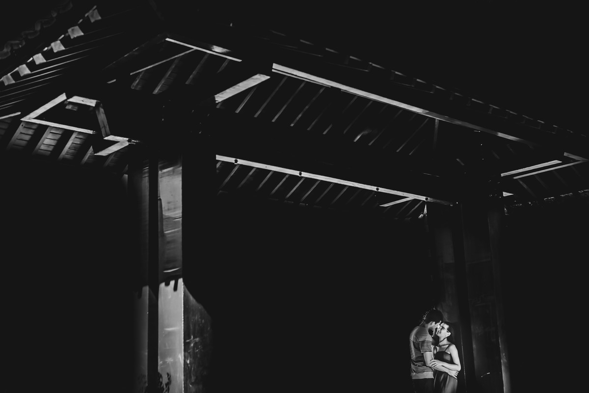 Foto dos Noivos abraçados e encostados na estrutura do telhado de madeira na Praça Japão no ensaio pré wedding - Curitiba - fotografia Cia P&B Produções 