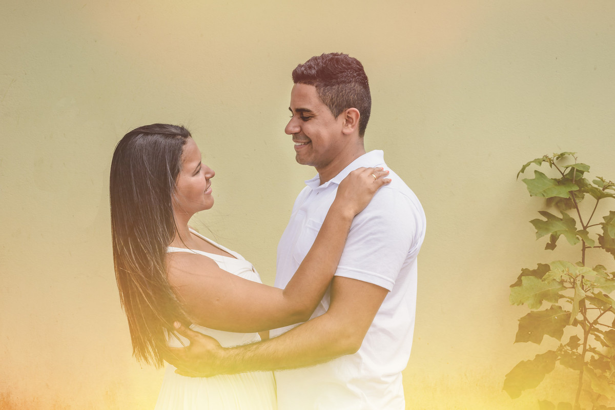 Foto dos noivos se abraçando e se olhando sorrindo com uma parede amarela de fundo no ensaio pré wedding - Itanhaém - SP - fotografia Cia P&B Produções