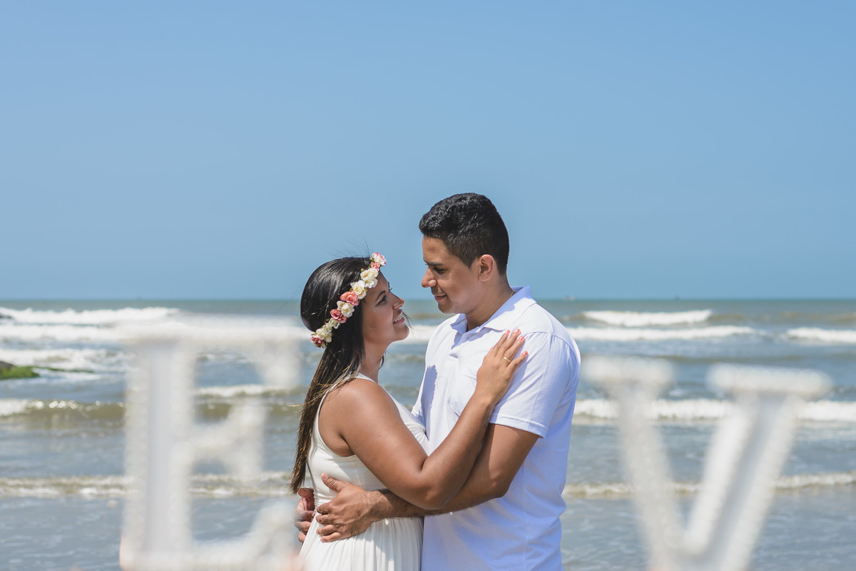 Foto da noiva com coroa de flores abraçada com o noivo na praia dos Pescadores se olhando no ensaio pré wedding - Itanhaém - SP - fotografia Cia P&B Produções