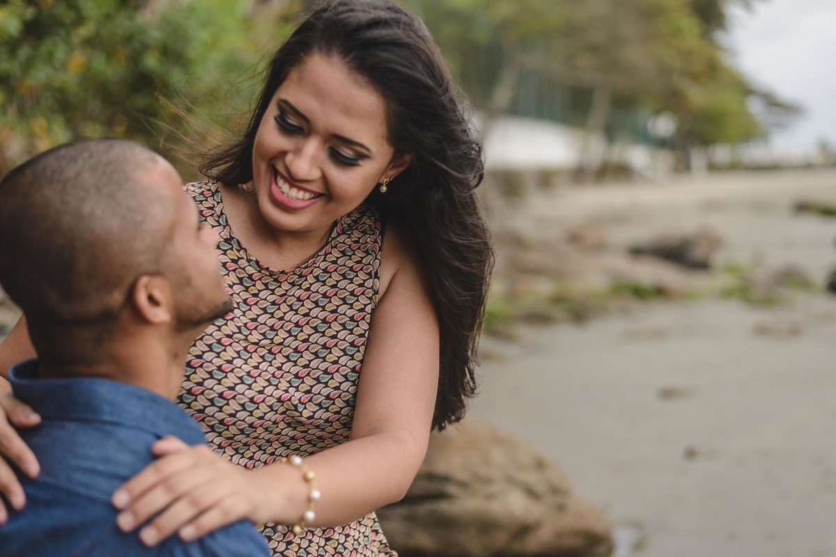 Foto dos Noivos na beira da praia sentados se olhando e sorrindo - Itanhaém - SP - fotografia Cia P&B Produções 