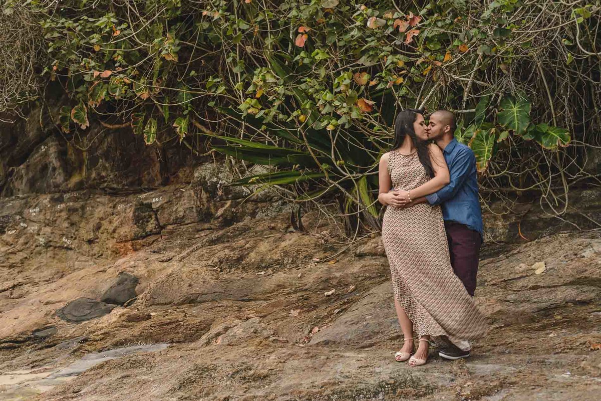 Foto dos Noivos abraçados e se beijando nas sobre as pedras com paisagem de folhagem - Itanhaém - SP - fotografia Cia P&B Produções  