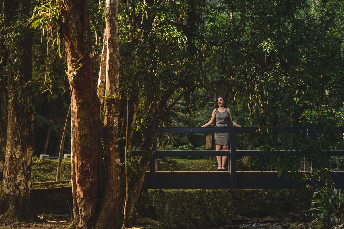 Ensaio de 15 anos Debutante na ponte com a luz do sol e a paisagem de árvores atrás dela - Poço das Antas - Mongaguá - SP - fotografia Cia P&B