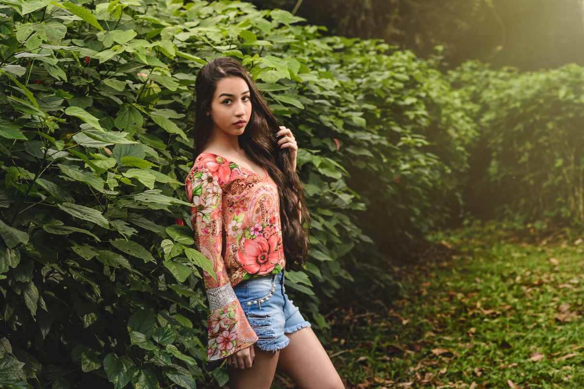 Ensaio de 15 anos debutante posando no caminho e muro feito de folhagens - Poço das Antas - Mongaguá - SP - fotografia Cia P&B