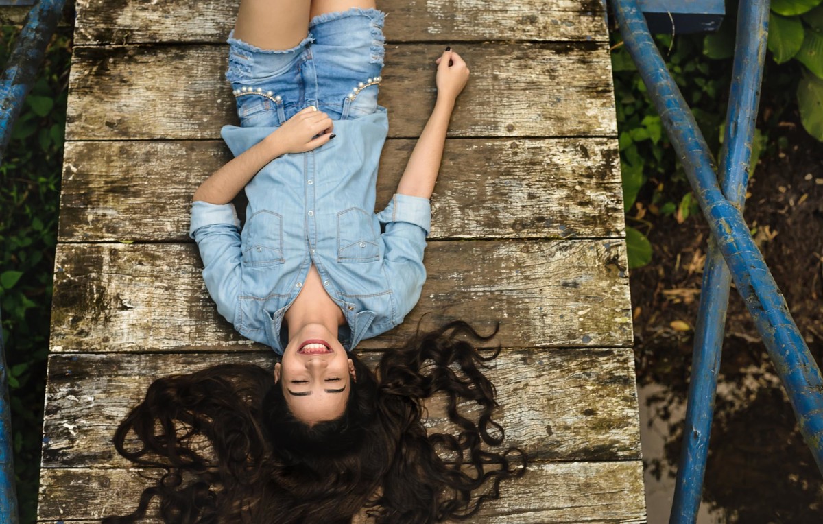 Ensaio de 15 anos debutante deitada na ponte sorrindo e de cabeça para baixo - Poço das Antas - Mongaguá - SP - fotografia Cia P&B