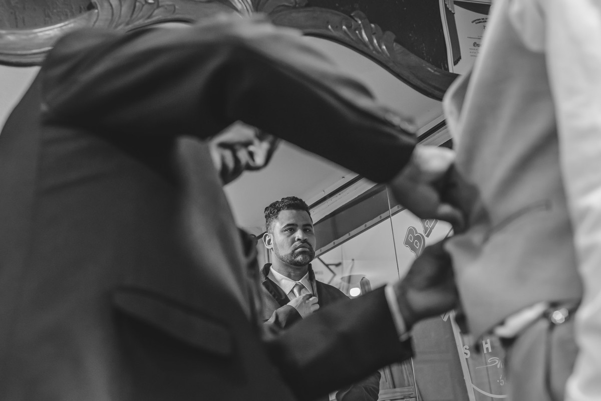 Foto do Irmão do noivo arrumando a gravata no espelho no making of do noivo - Mongaguá - Sp- fotografia Cia P&B Produções