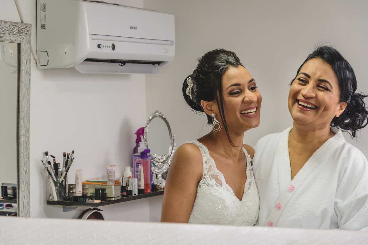 Foto da Noiva e sua mãe sorrindo no espelho no making of Drieli Designers - Mongaguá - Sp- fotografia Cia P&B Produções
