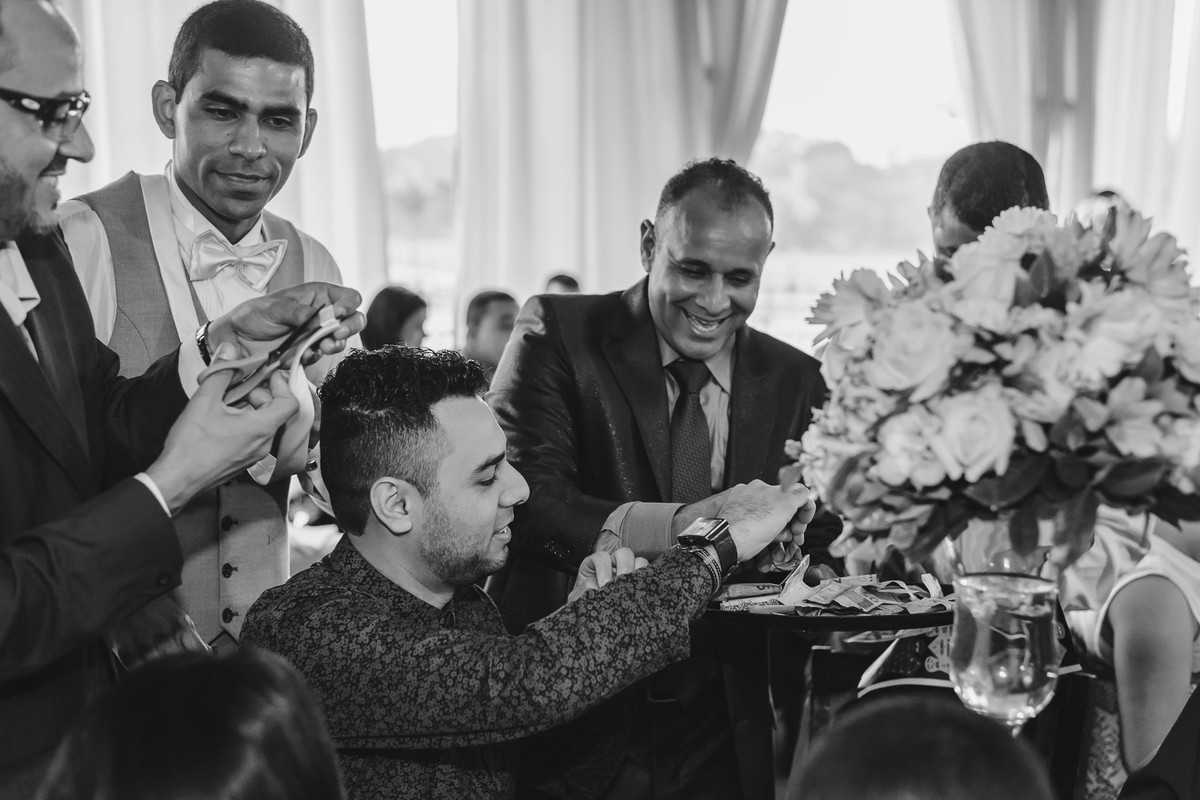 Foto do pai do noivo e noivo passando a gravata na festa para os convidados - Hípica de Itanhaém - fotografia Cia P&B Produções