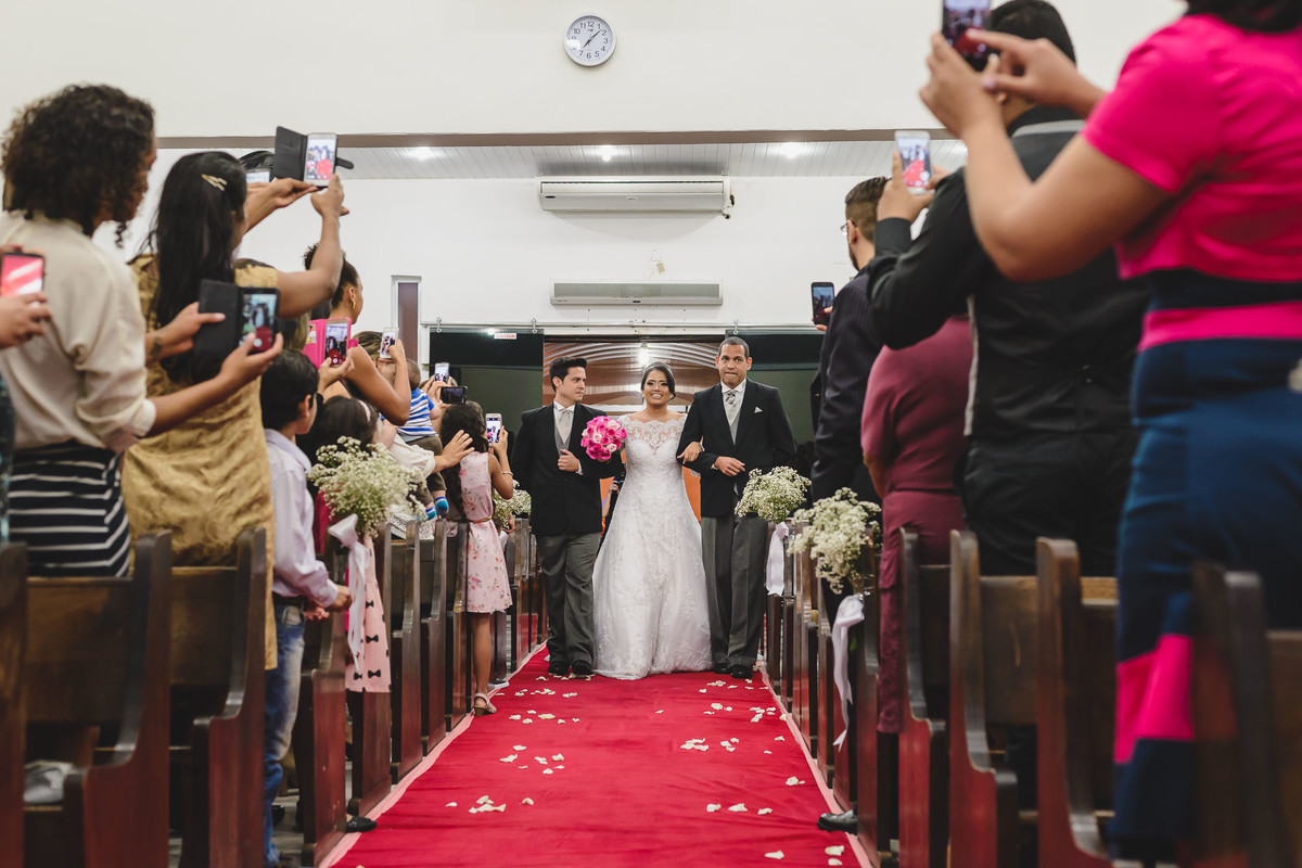 Noiva entrando na igreja com o pai e padastro em Praia Grande - SP - fotografia Cia P&B Produções 