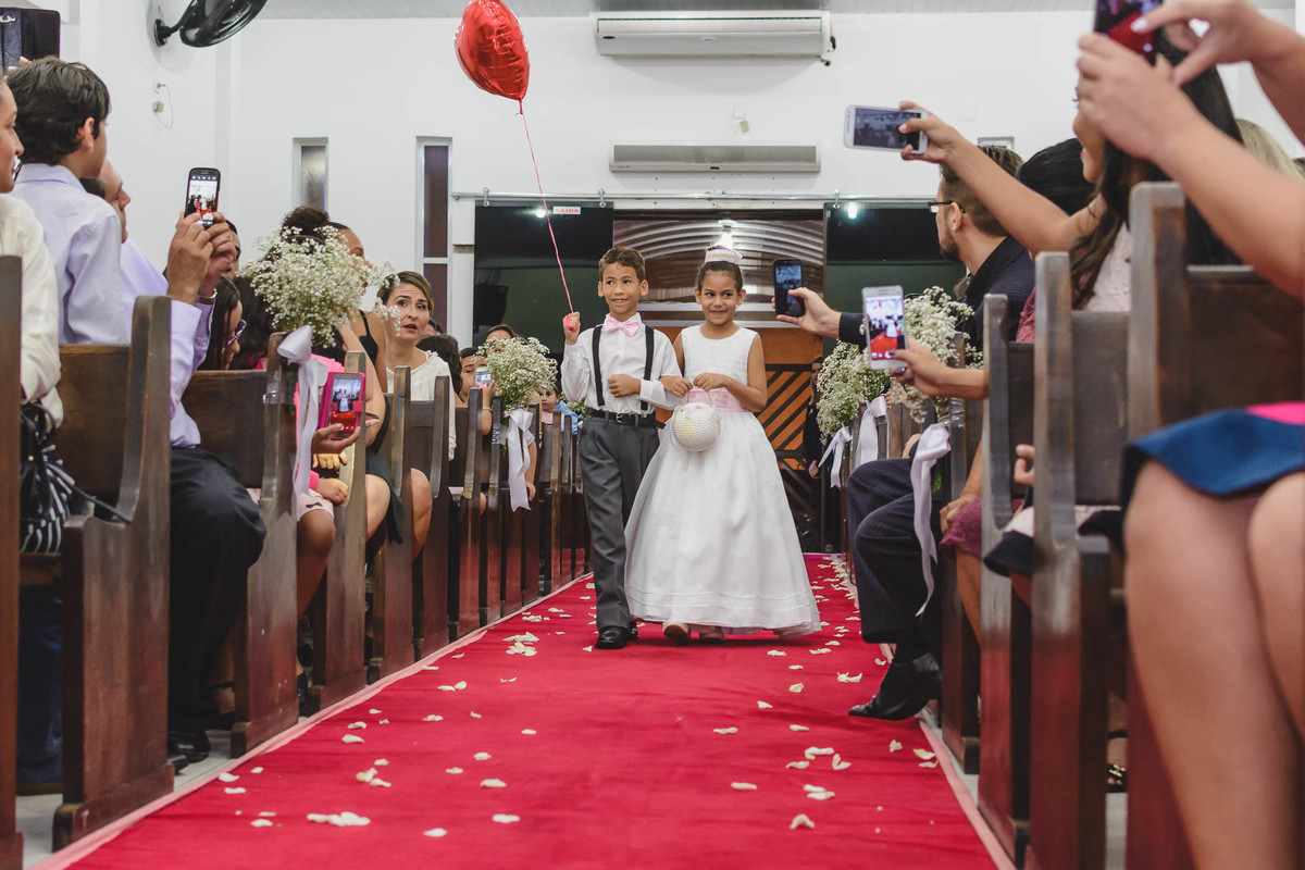 Pagem e daminha entrando com as alianças e balão de coração na igreja na cerimônia de casamento em Praia Grande - SP - fotografia Cia P&B Produções 