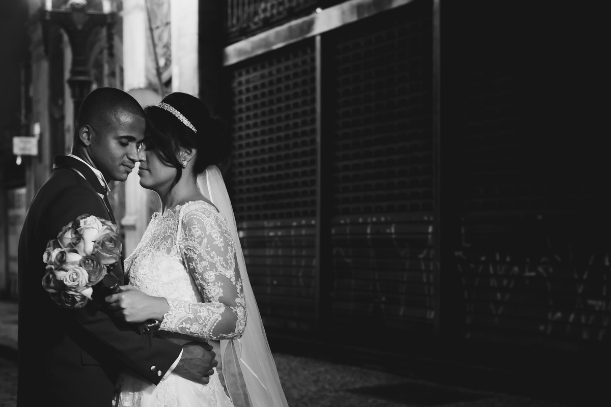 Ensaio dos noivos pós cerimônia se abraçando de olhos fechados e a noiva segurando o buquê no centro de Santos - SP - Bolsa do Café - fotografia Cia P&B Produções 