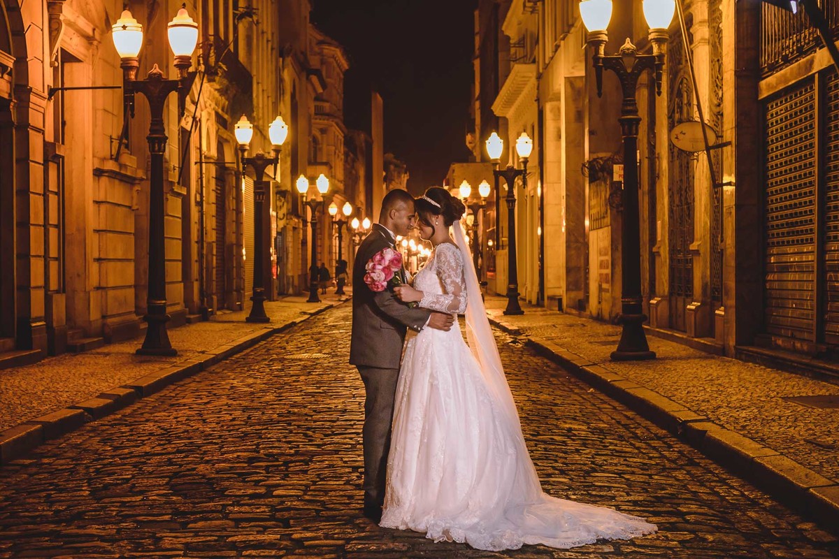Noivos abraçados na rua do centro de Santos - SP, com os postes de luz amarelas no ensaio pós cerimônia - Bolsa do café - fotografia Cia P&B Produções 