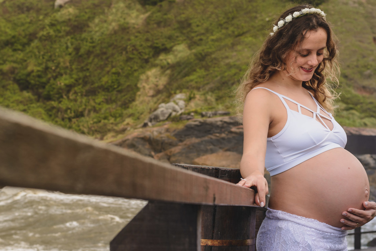 Foto da gestante olhando para a barriga.Ensaio de gestante feito pela Cia  P&B Produções Itanhaém - SP