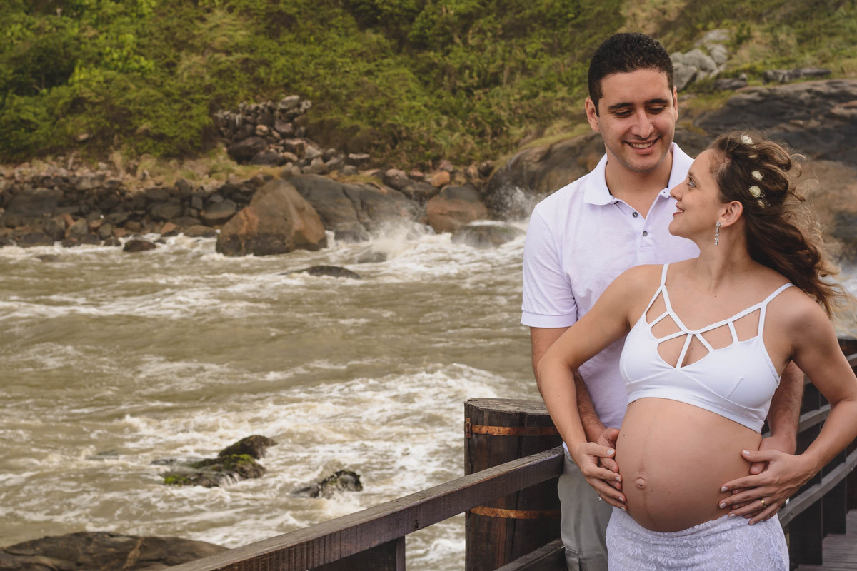 Foto da gestante e seu marido se olhando.Ensaio de gestante feito pela Cia P&B Produções Itanhaém - SP