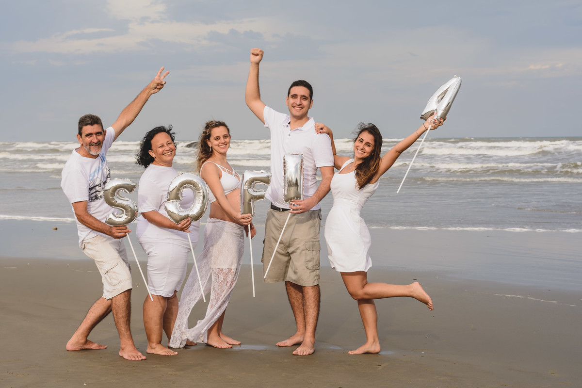 foto da gestante com a família segurando balões com o nome do bebê. Ensaio de gestante feito pela Cia P&B Produções Itanhaém - SP