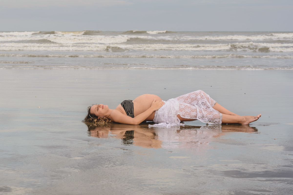 foto da gestante deitada na praia. Ensaio de gestante feito pela Cia P&B Produções Itanhaém - SP