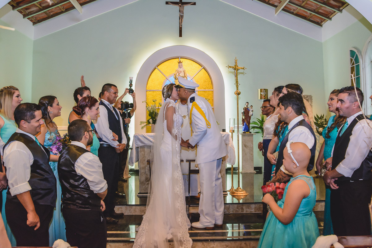 Foto do beijo dos noivos no altar durante a cerimônia - Praia Grande - SP -Capela  Santa Matilde - Cia P&B Produções