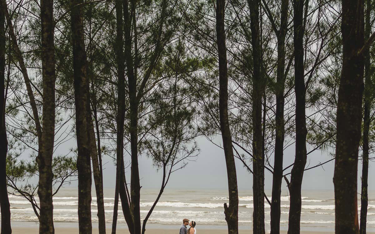 Casal se beijando na praia entre as árvores./Praia de Peruíbe - Cia P&B Produções