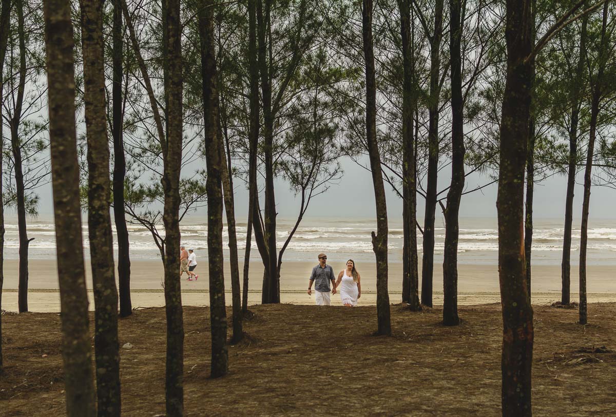 Casal caminhando de mãos dadas./Praia de Peruíbe - Cia P&B Produções