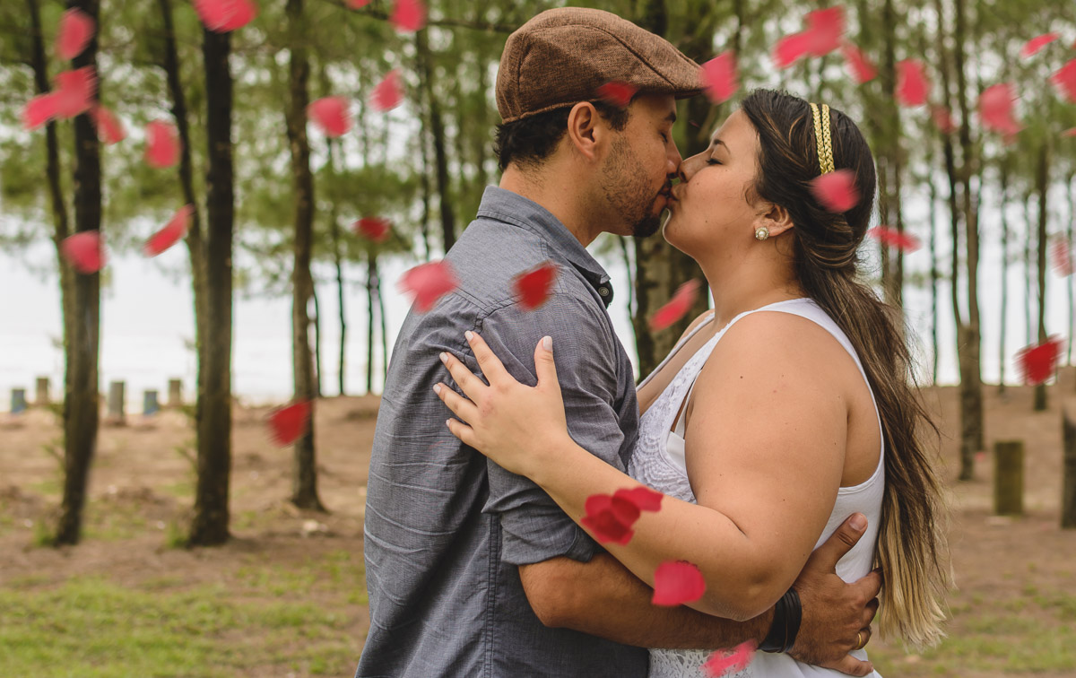 Casal se beijando na praia com pétalas de flores./Praia de Peruíbe - Cia P&B Produções