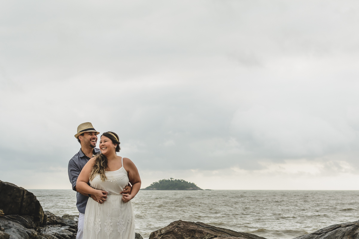 casal entre as pedras e o mar em ensaio pré-wedding/Praia de Peruíbe - Cia P&B Produções