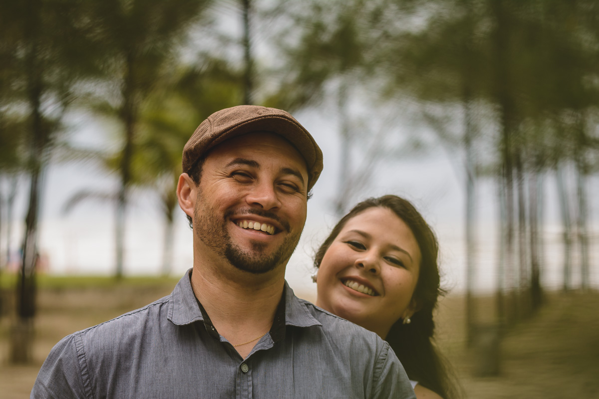 Casal sorrindo entre as árvores./Praia de Peruíbe - Cia P&B Produções