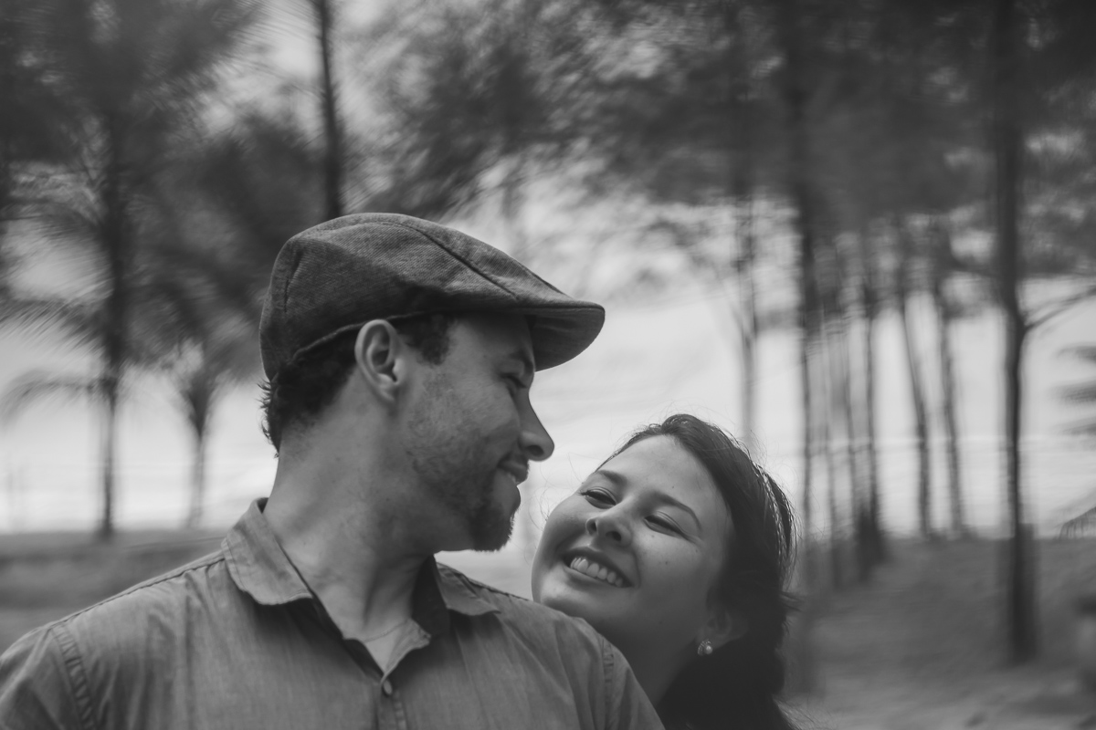 Casal se olhando na praia entre as árvores./Praia de Peruíbe - Cia P&B Produções