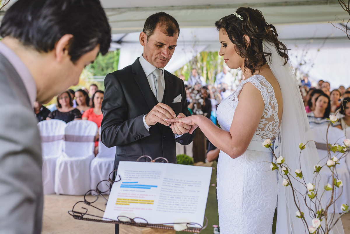 Noivo colocando a aliança no dedo da noiva na cerimônia - Itapevi - SP - fotografia Cia P&B Produções - Chácara Brilho da Lua