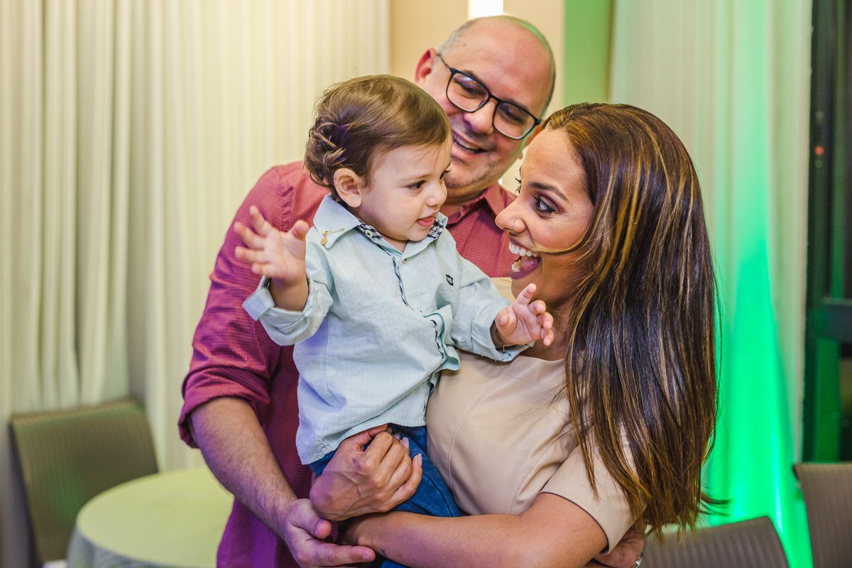 mãe e pai brincando com o filho no colo