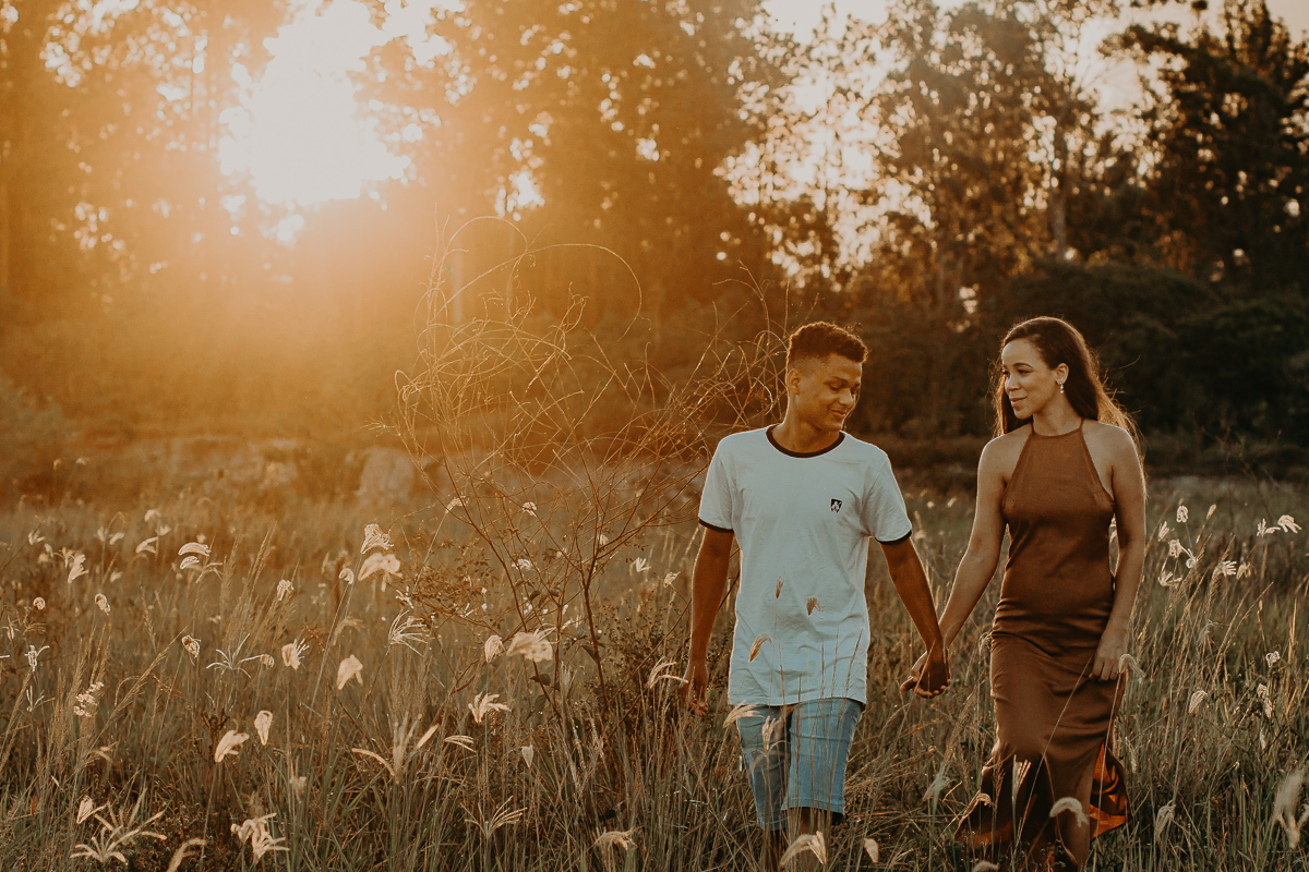 noivos caminhando na vegetação e ao fundo o por do sol