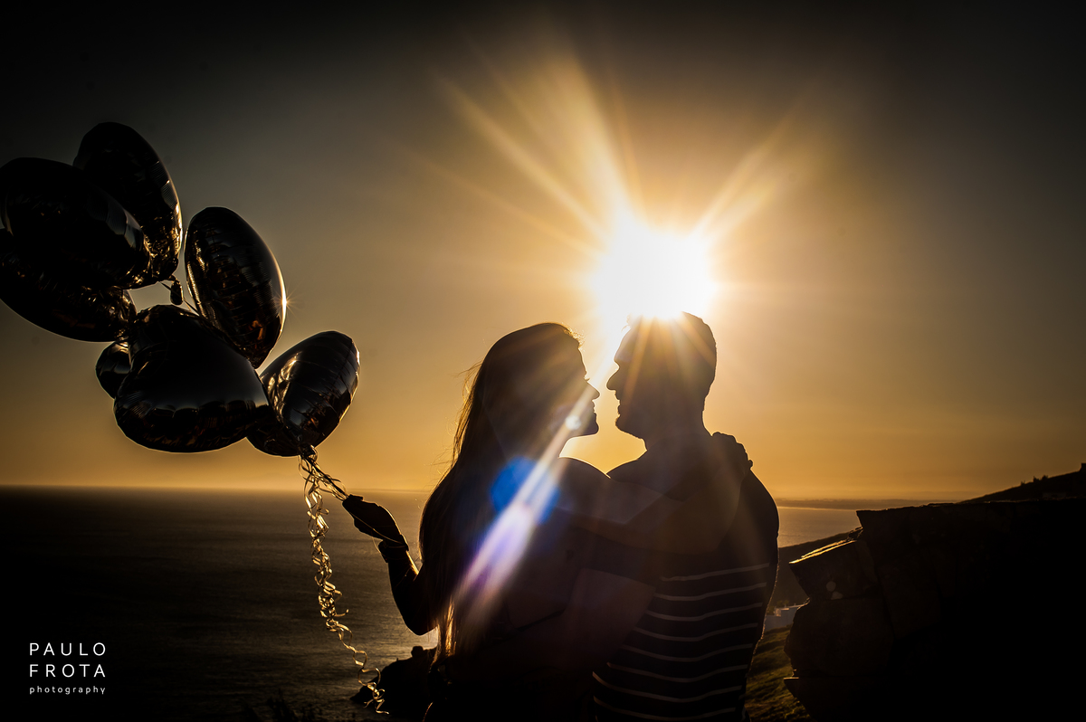 casal com bolas de coração, de silhuetas. Sol se pondo.