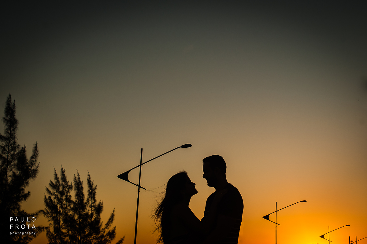 silhueta de casal, com por do sol. setas feitas com a sobra do poste indicam o casal.