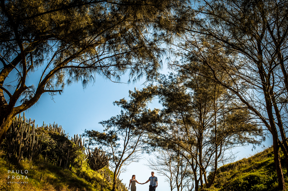casal emoldurado com arvores, de mãos dadas e céu azul atrás