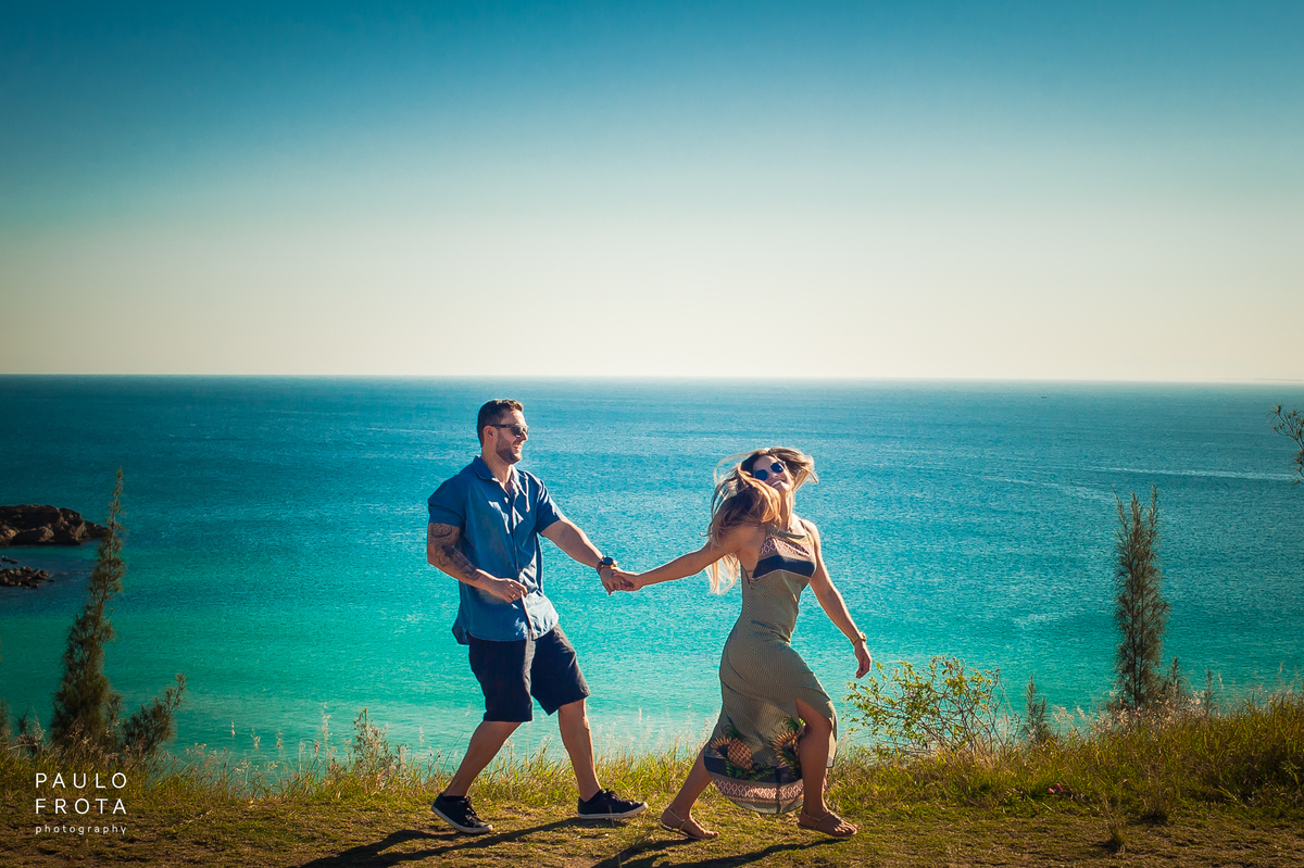 casal correndo na beira da praia. Mar atrás
