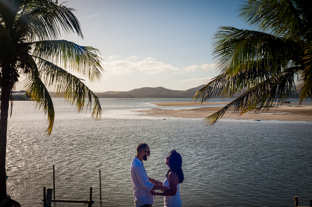 casal no centro da imagem, se olhando. moldura de coqueiros