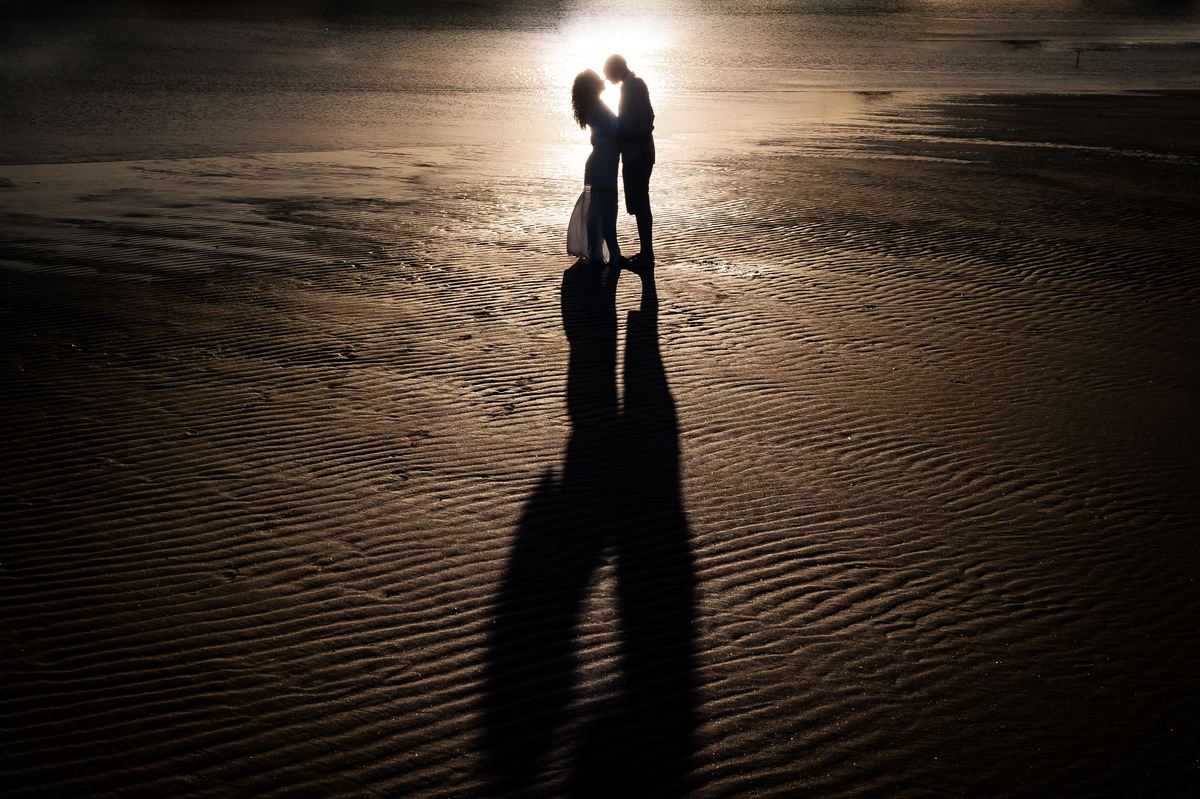 casal se beijando em silhueta. reflexo do sol atrás sob a água.