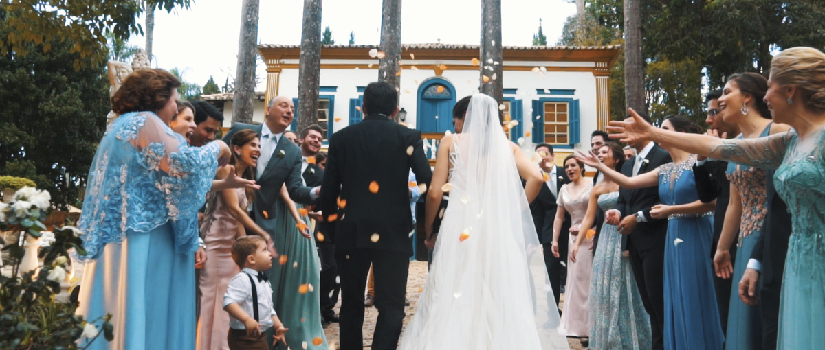 Noivos caminhando sob chuva de pétalas em cerimônia de casamento de dia na Fazenda Santa Barbara