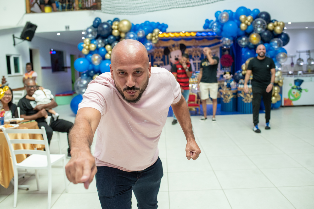 Foto de festa infantil temática do Mickey e da Minnie, com decoração vermelha, preta e amarela, bolo temático e crianças sorrindo, capturada por fotógrafo profissional especializado em eventos infantis.