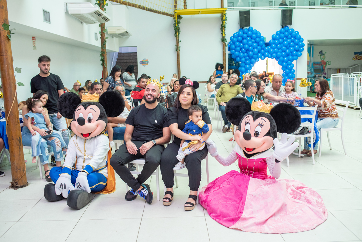 Foto de festa infantil temática do Mickey e da Minnie, com decoração vermelha, preta e amarela, bolo temático e crianças sorrindo, capturada por fotógrafo profissional especializado em eventos infantis.