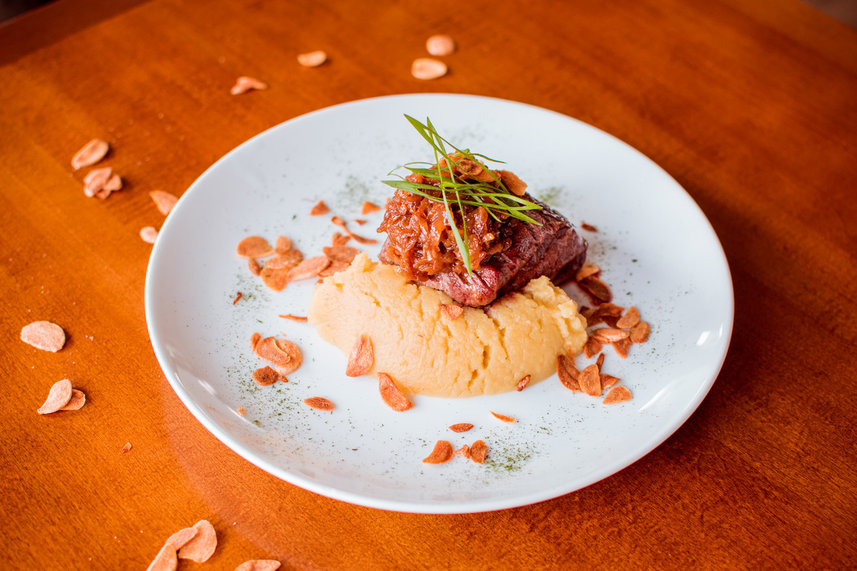 Filé mignon grelhado, purê de batata doce, cebola caramelizada e chips de alho.