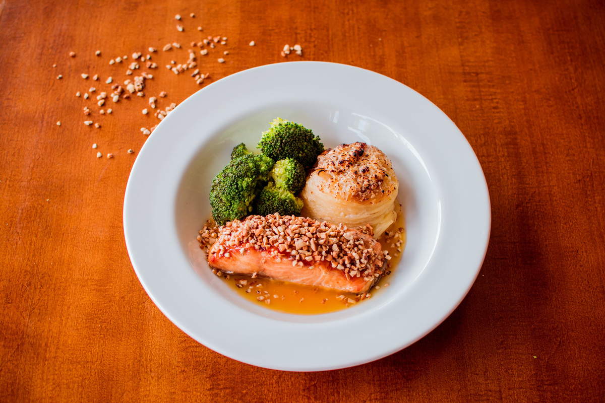 Salmão grelhado em crosta de castanha de caju, mil folhas de batata e molho de laranja com gengibre.