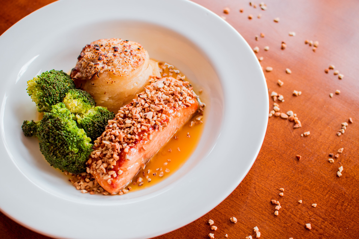 Salmão grelhado em crosta de castanha de caju, mil folhas de batata e molho de laranja com gengibre.