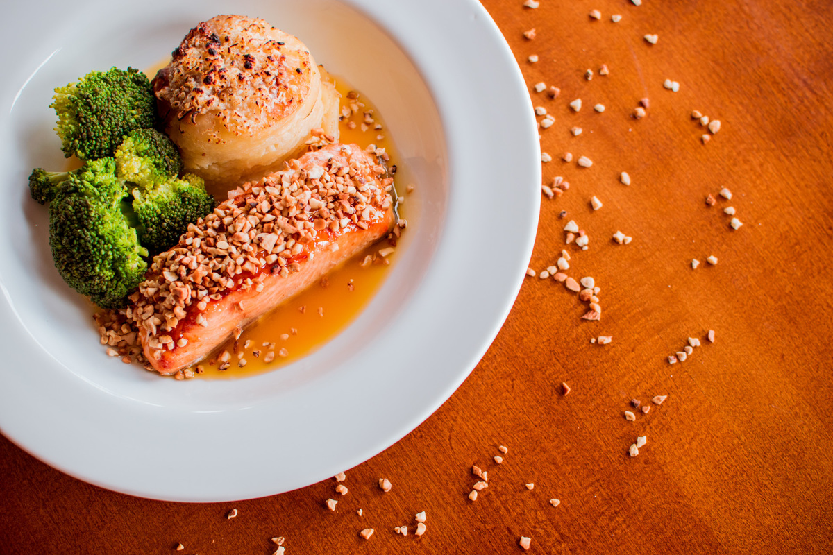 Salmão grelhado em crosta de castanha de caju, mil folhas de batata e molho de laranja com gengibre.