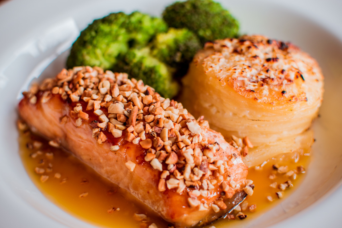 Salmão grelhado em crosta de castanha de caju, mil folhas de batata e molho de laranja com gengibre.