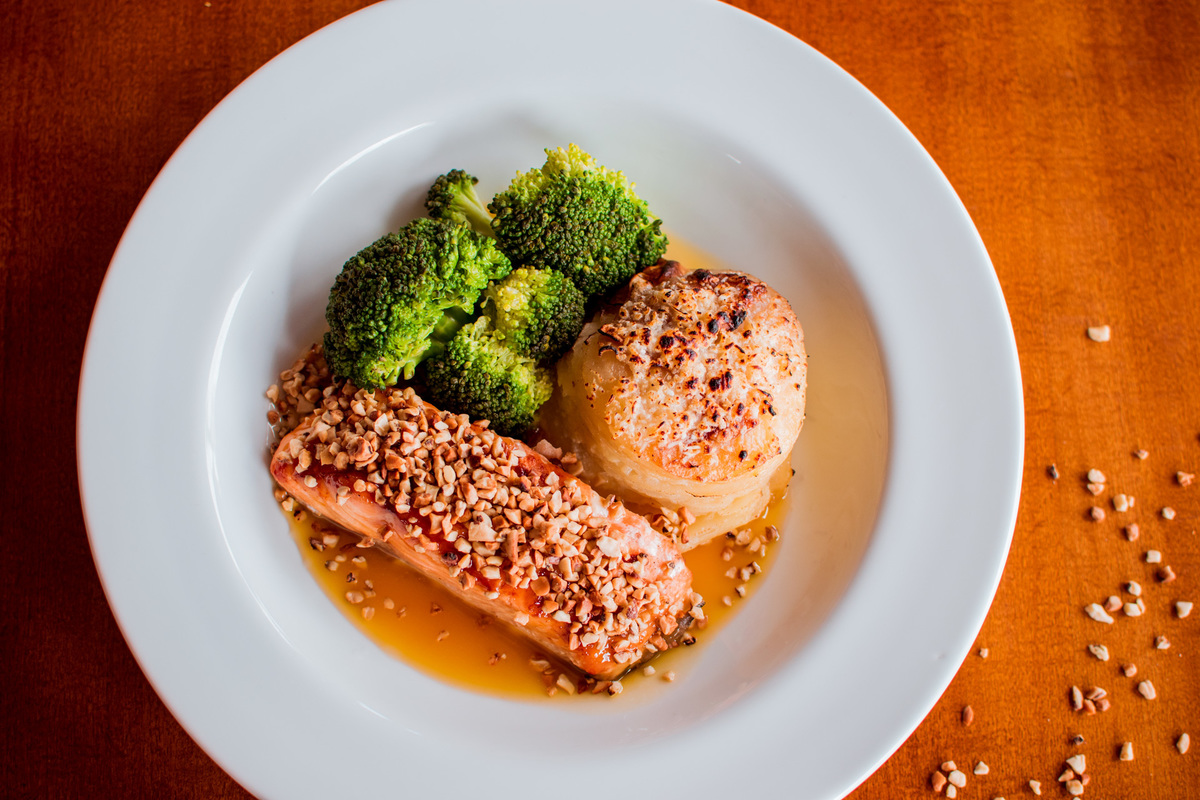 Salmão grelhado em crosta de castanha de caju, mil folhas de batata e molho de laranja com gengibre.