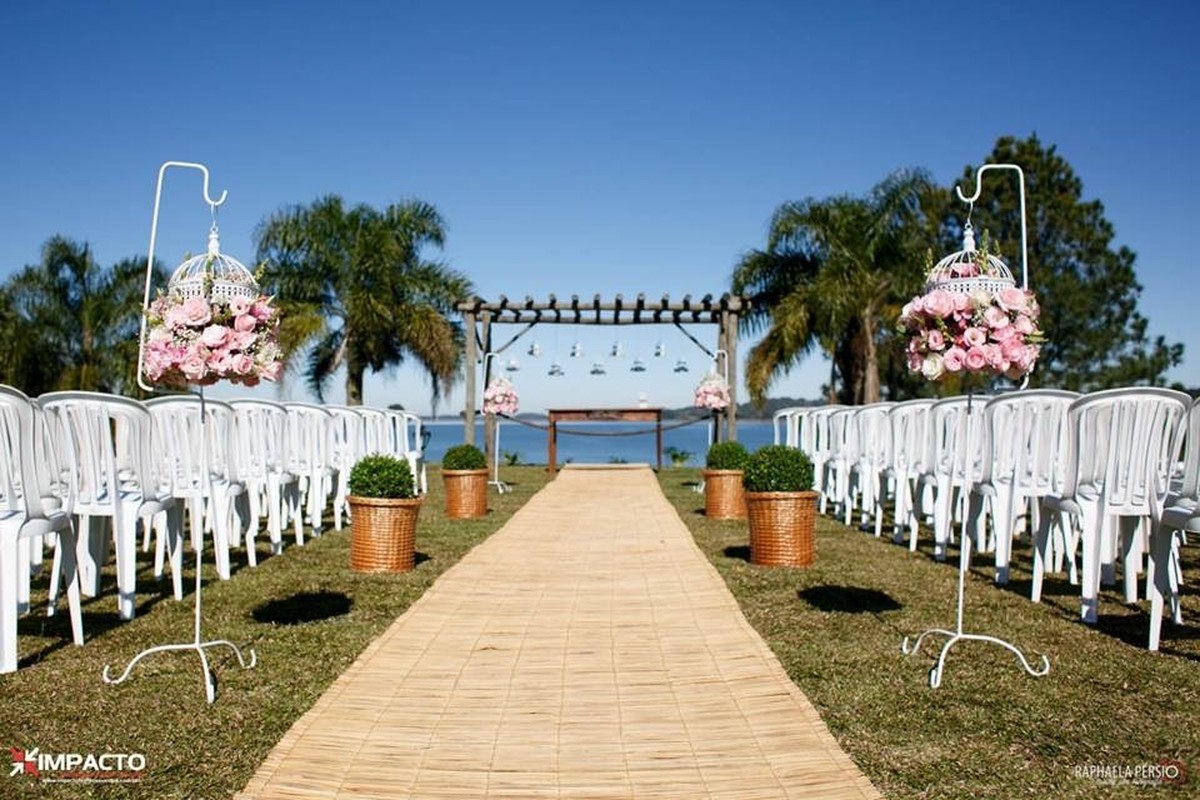 Corredor de casamento ao ar livre com tapete rústico e arranjos suspensos em gaiolas