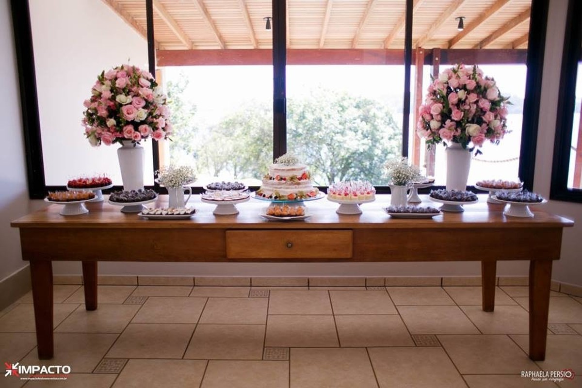 Mesa de doces de madeira com arranjos em vasos de porcelana branca